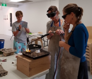 Workshop participants learning to pour molten silver into a carved cuttlebone cast.