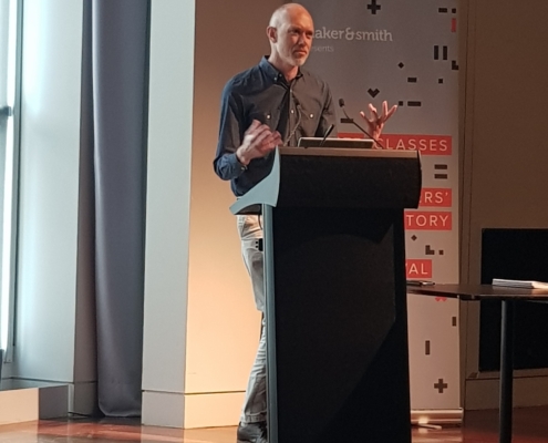 A man stands at a lectern with gesturing hands
